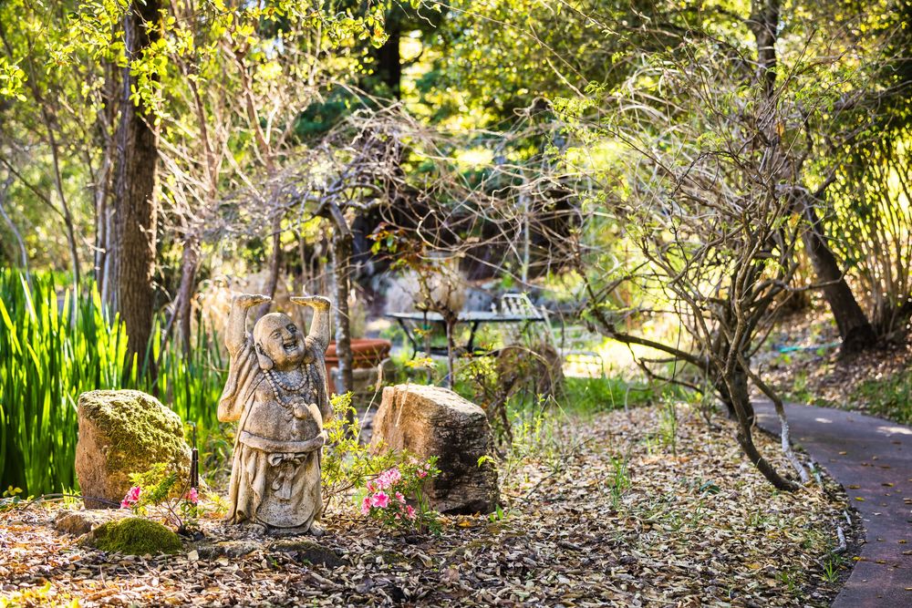 A winding garden path leads through lush greenery and trees in a tranquil botanical setting.