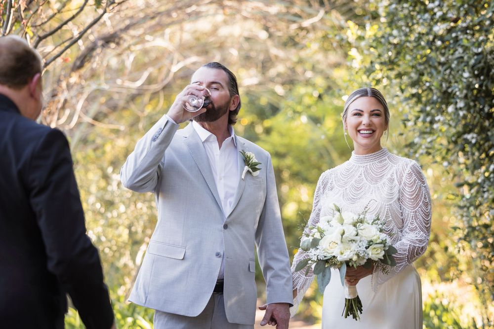 Wedding celebration in a lush garden setting with natural sunlight filtering through trees.