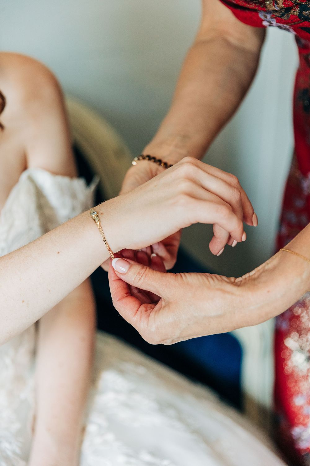 Close-up view of hands holding and adjusting a white wedding dress during preparation.