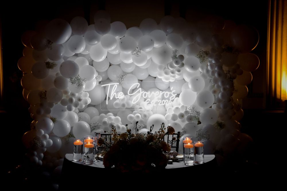Wedding reception venue decorated with ethereal white balloon cloud installation and ambient lighting.