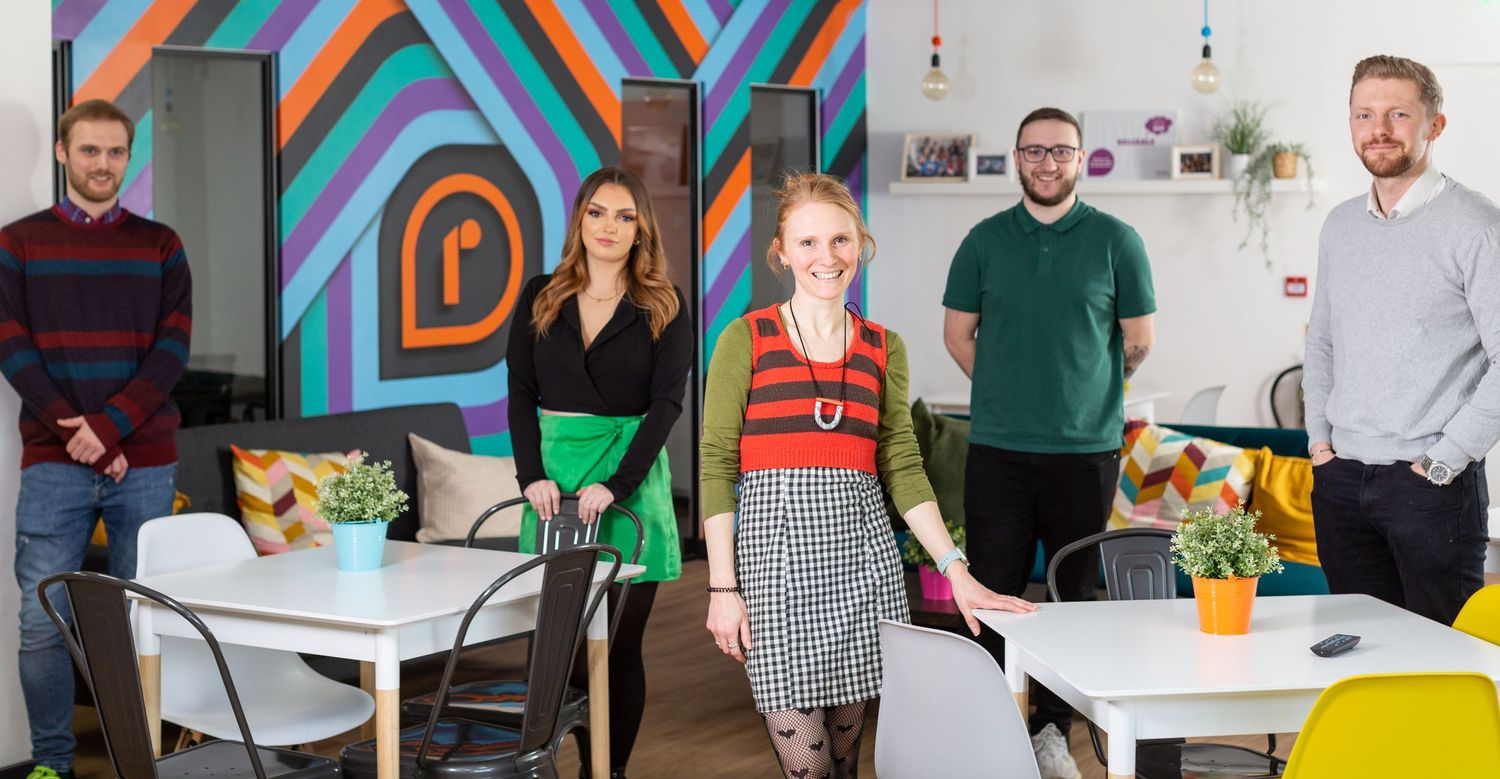 A modern office space with colorful geometric wall art and white furnishings.