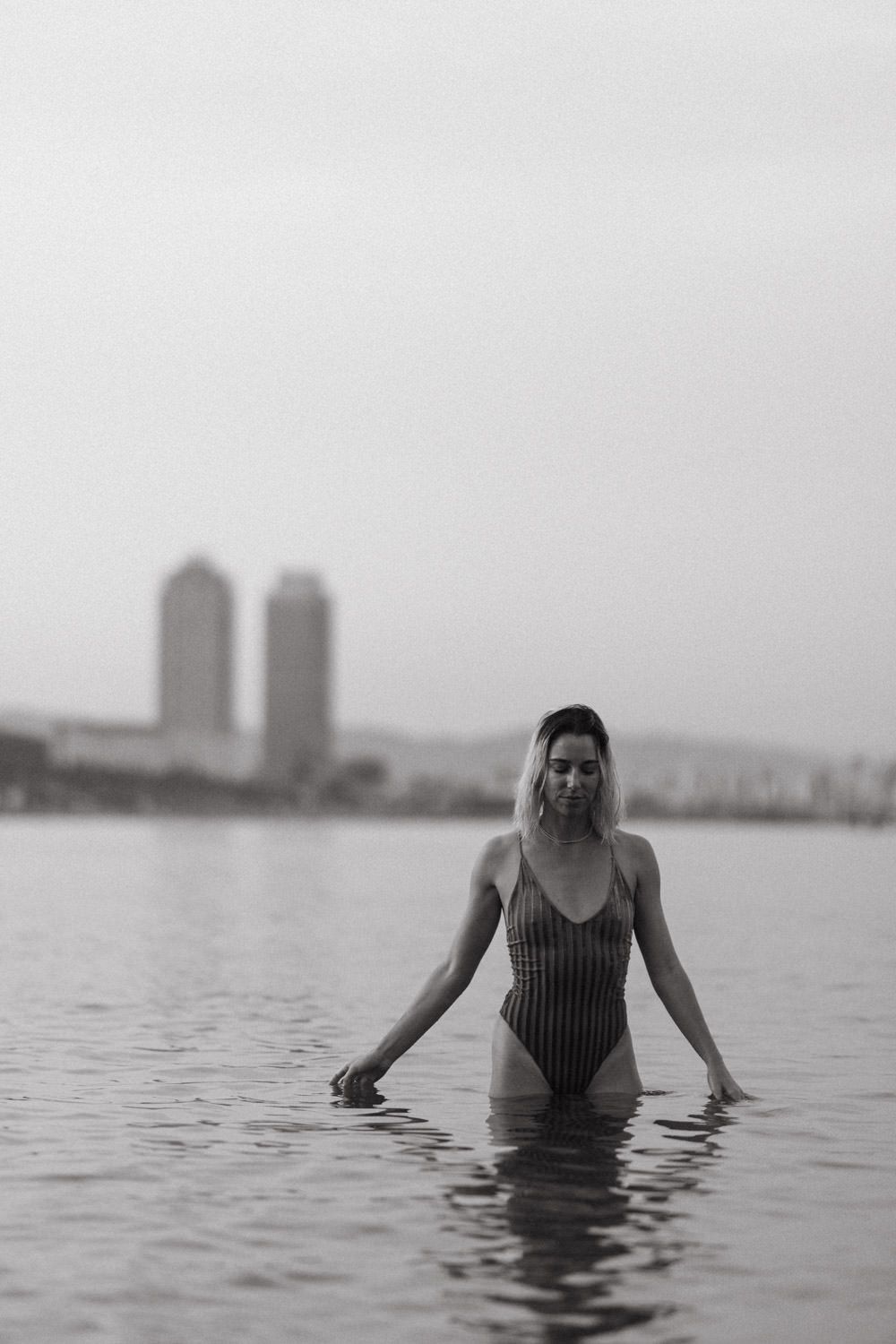 A series of minimalist black and white photos of someone wading in calm water.