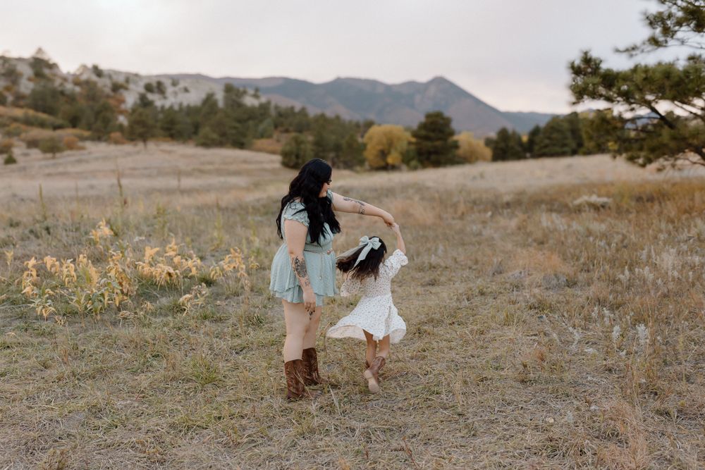 Joyful spinning dance moment captured in a scenic mountain field at dusk. Colorado Springs Photographer.