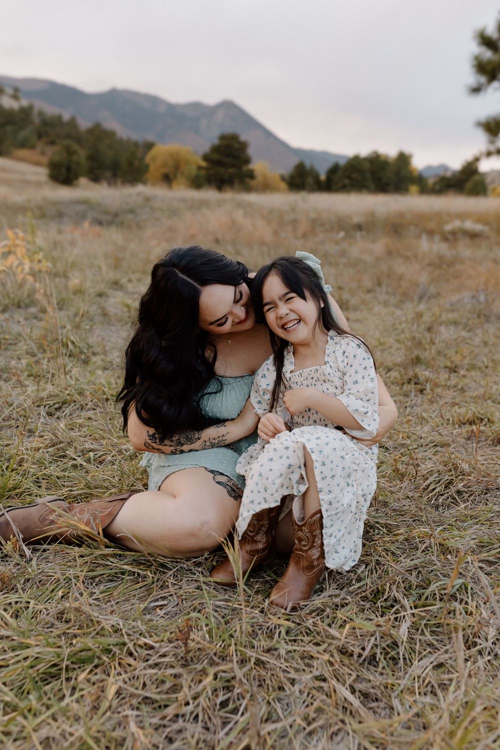 A heartwarming outdoor photo session in a mountain field shows intimate bonding and laughter. Colorado Springs Photographer.