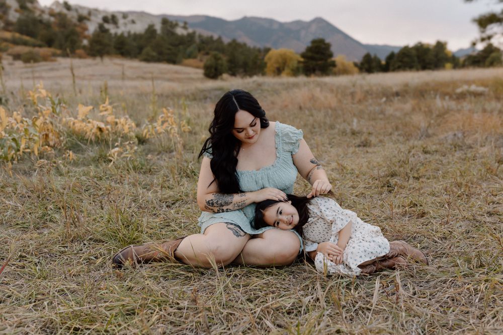 A tender moment captured in a field with mountains and autumn trees in the background. Colorado Springs Photographer.