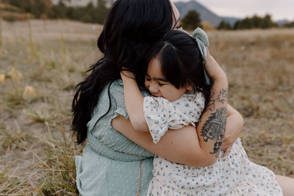 Tender embrace between parent and child in casual clothing outdoors. Colorado Springs Photographer.