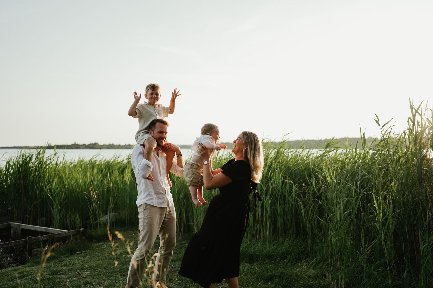 Family having fun together in a grassy field by the water during sunset.