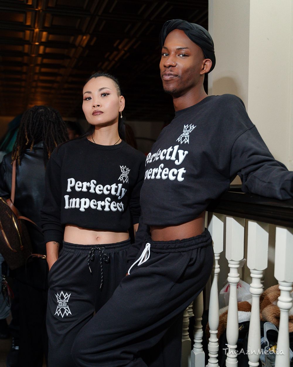 Two models wearing matching black Perfectly Imperfect crop top sweaters pose together.