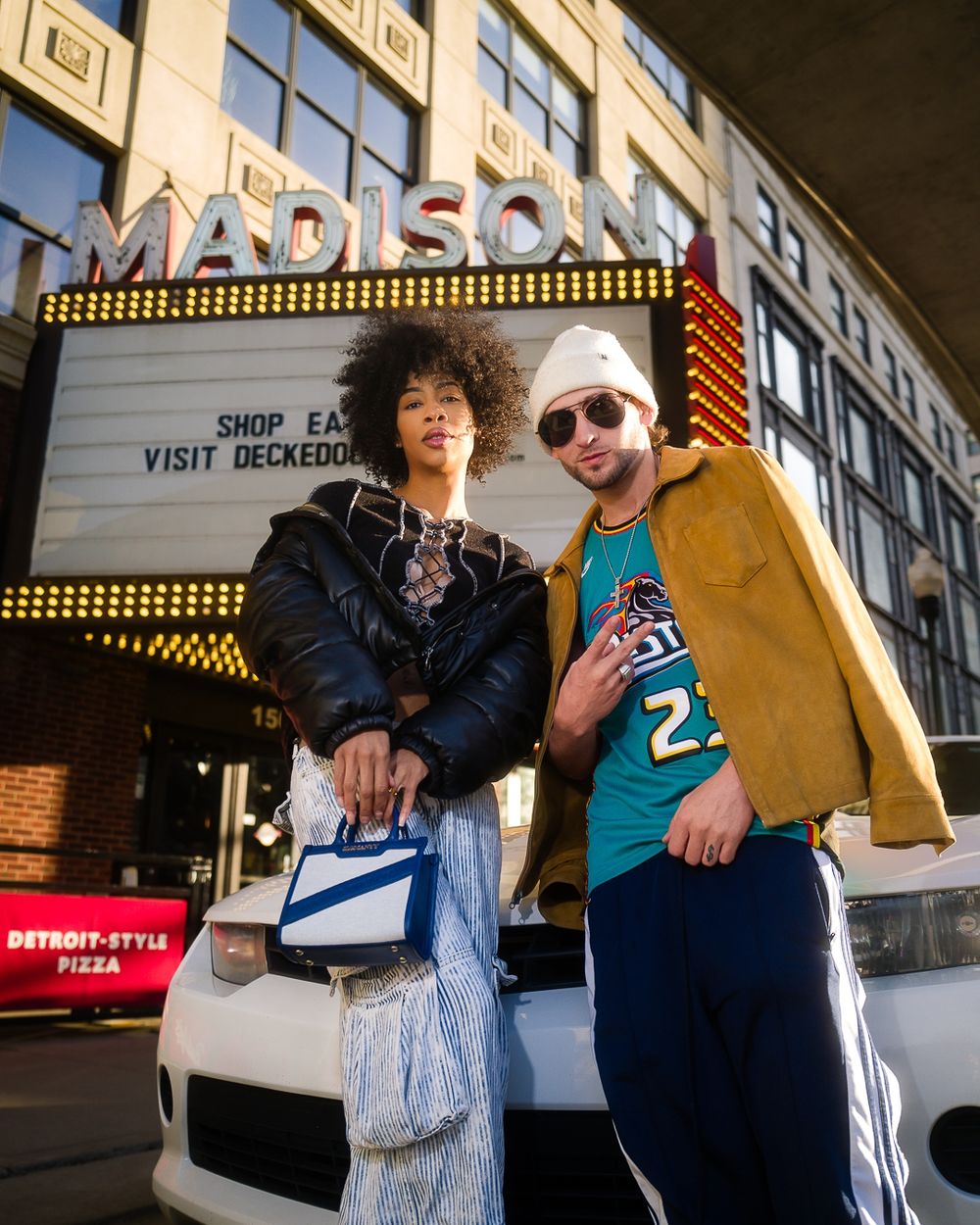 Two friends pose casually in front of Madison theater marquee sign.