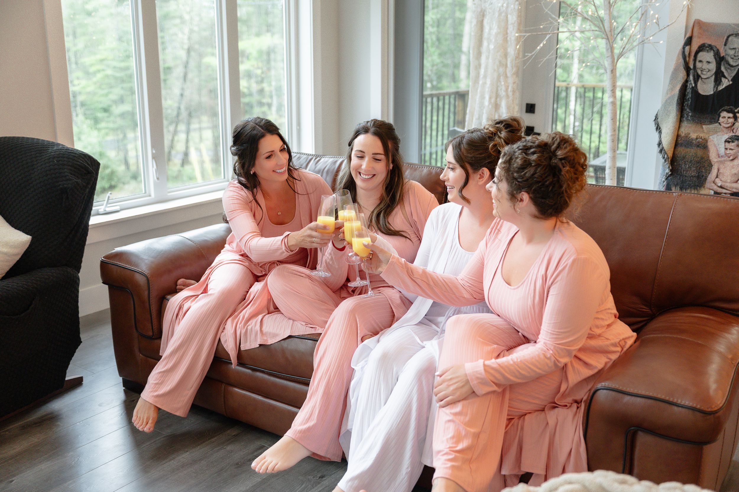 bride and bridesmaids getting ready for the day sharing a cheers with their mimosas.
