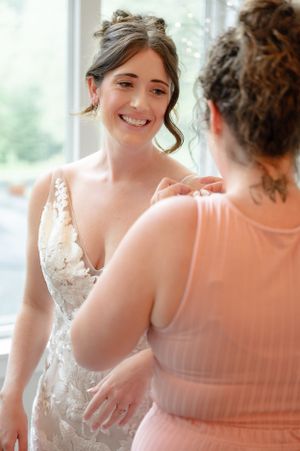 maid of honour helping bride with the finishing touches on her outfit on her wedding morning.