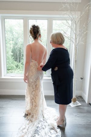 brides mother zipping bride into her dress on her wedding day