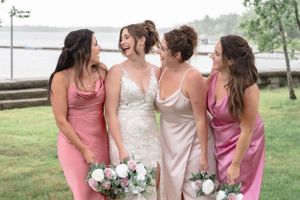 bride and her bridesmaids laughing with one another by the water