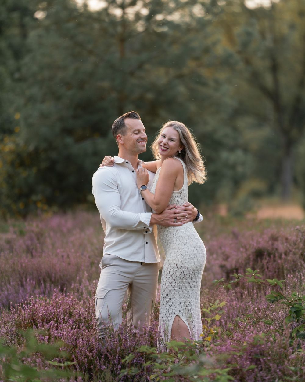 Romantic couple shares intimate moments in a blooming purple heather field at sunset.