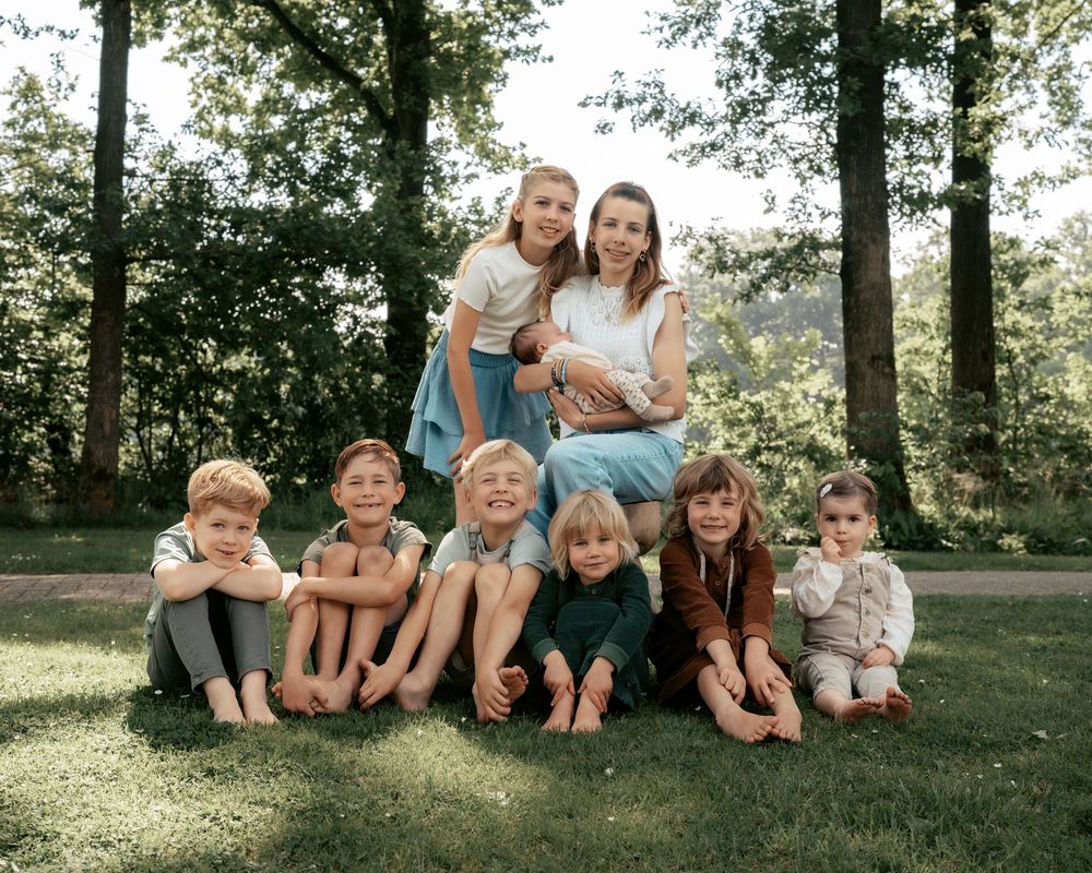 A group photo of family members sitting together on grass in a park setting.