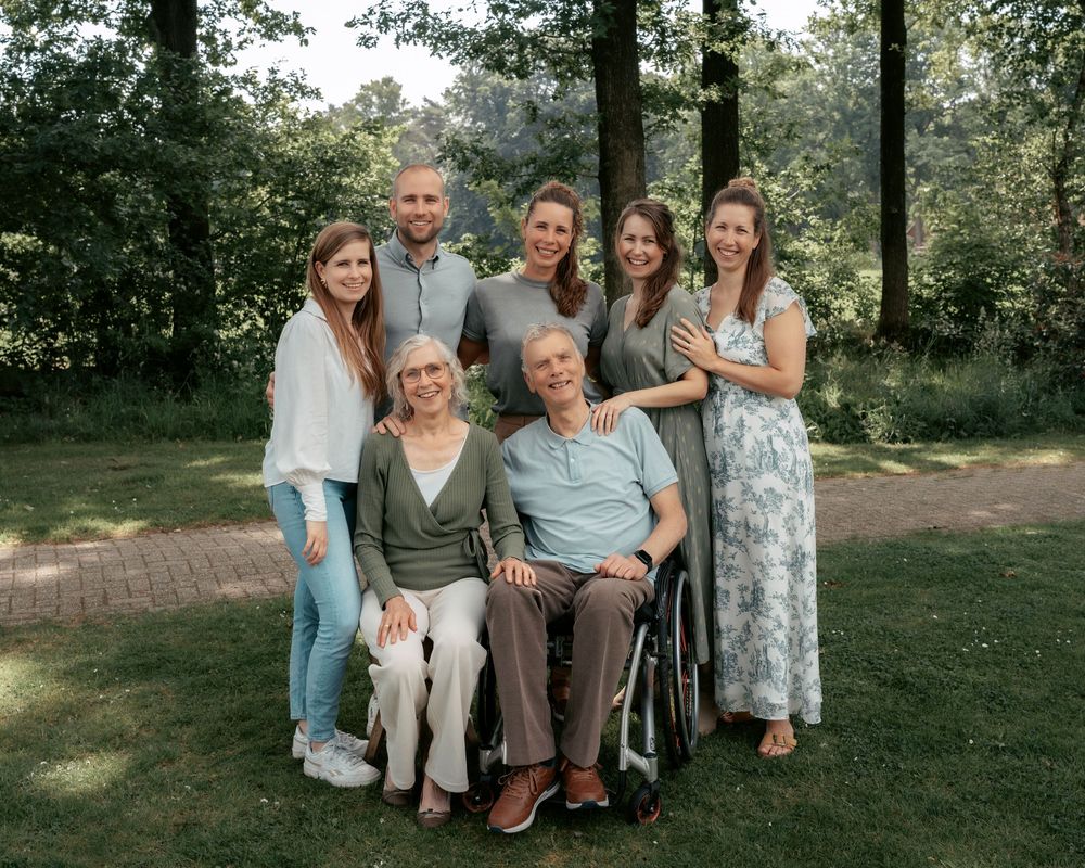 Extended family gathering photo with multiple generations posed together in a park setting.