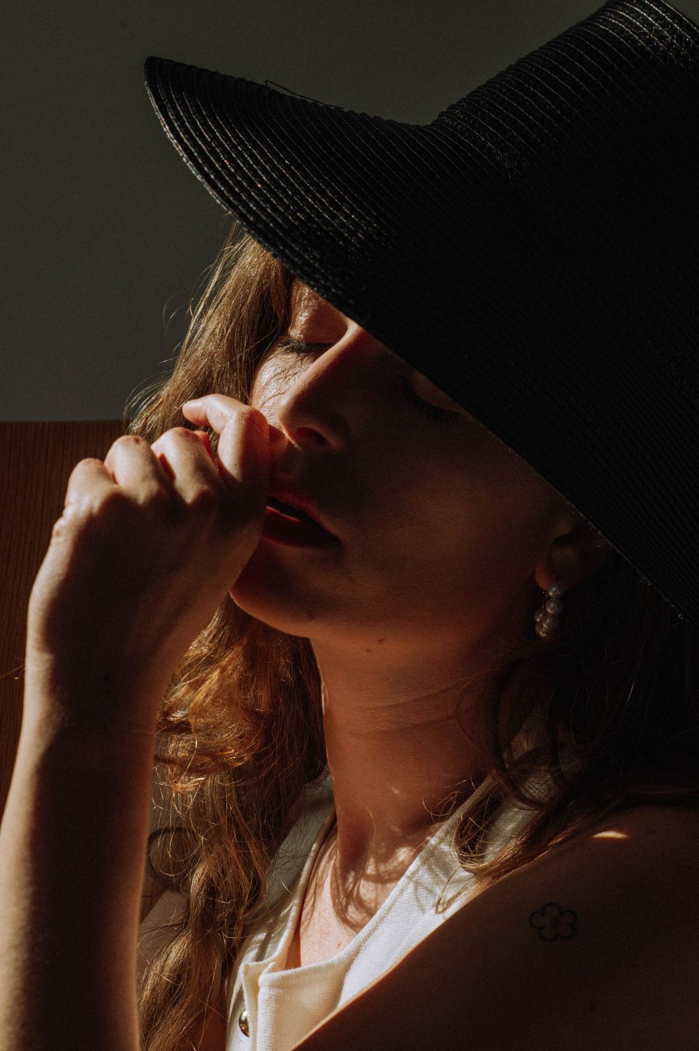 Artistic portrait of someone in a black hat with dramatic side lighting.