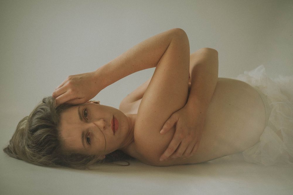 Intimate boudoir portrait with soft lighting and white fabric.