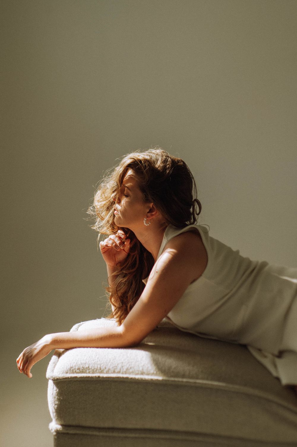 Moody portrait of someone reclining on a couch in soft lighting.