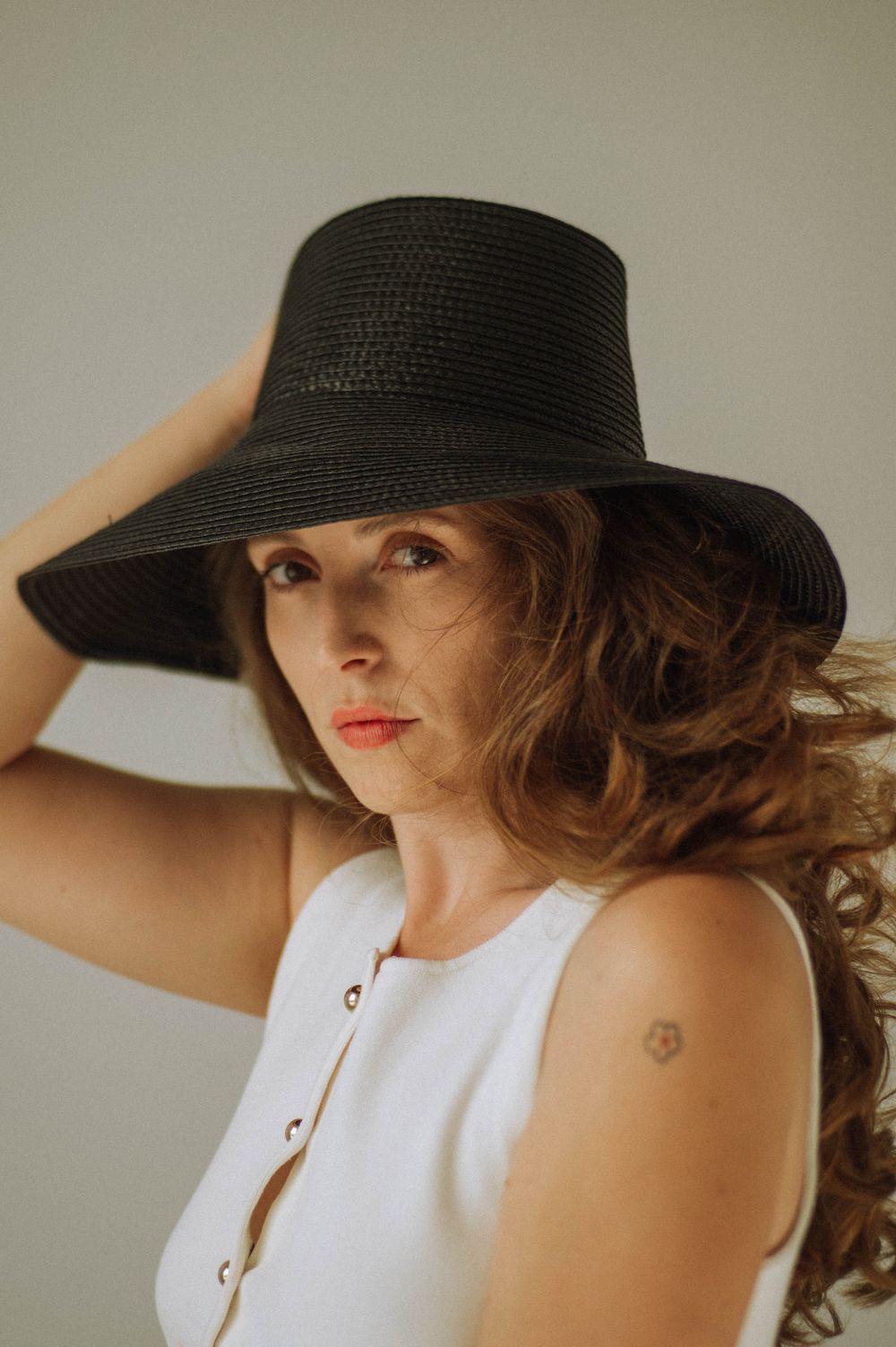 Fashion portrait featuring a wide-brim black hat and white tank top.