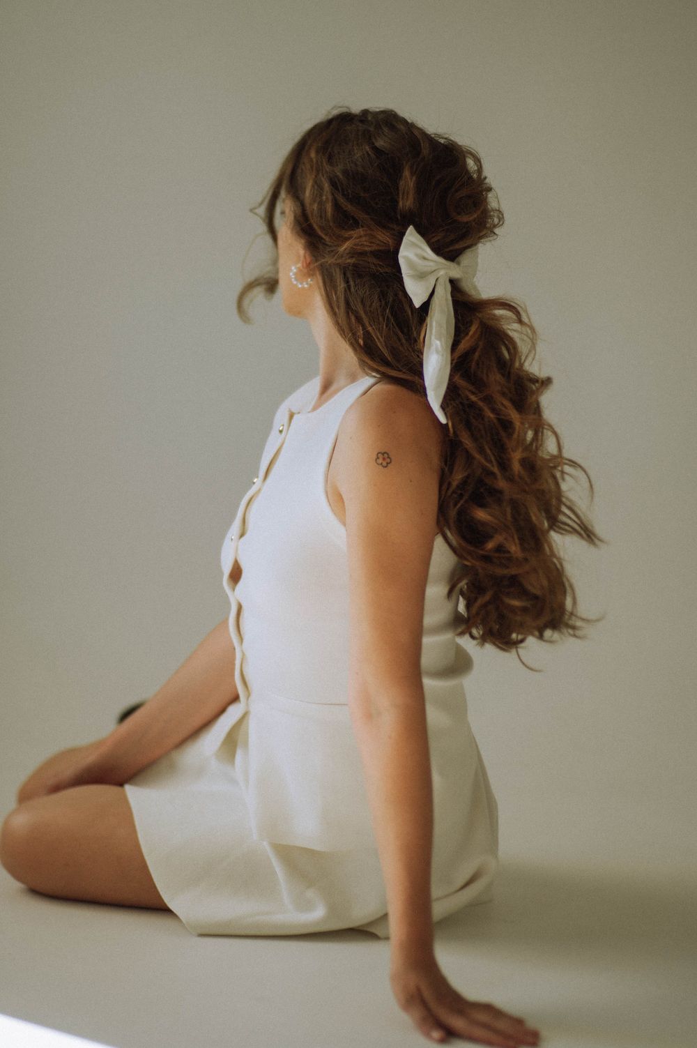 Elegant portrait in white dress with hair ribbon and side profile pose.