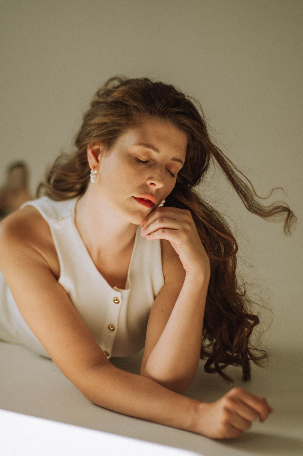 Person in white top lying on table with soft lighting creating dreamy atmosphere.