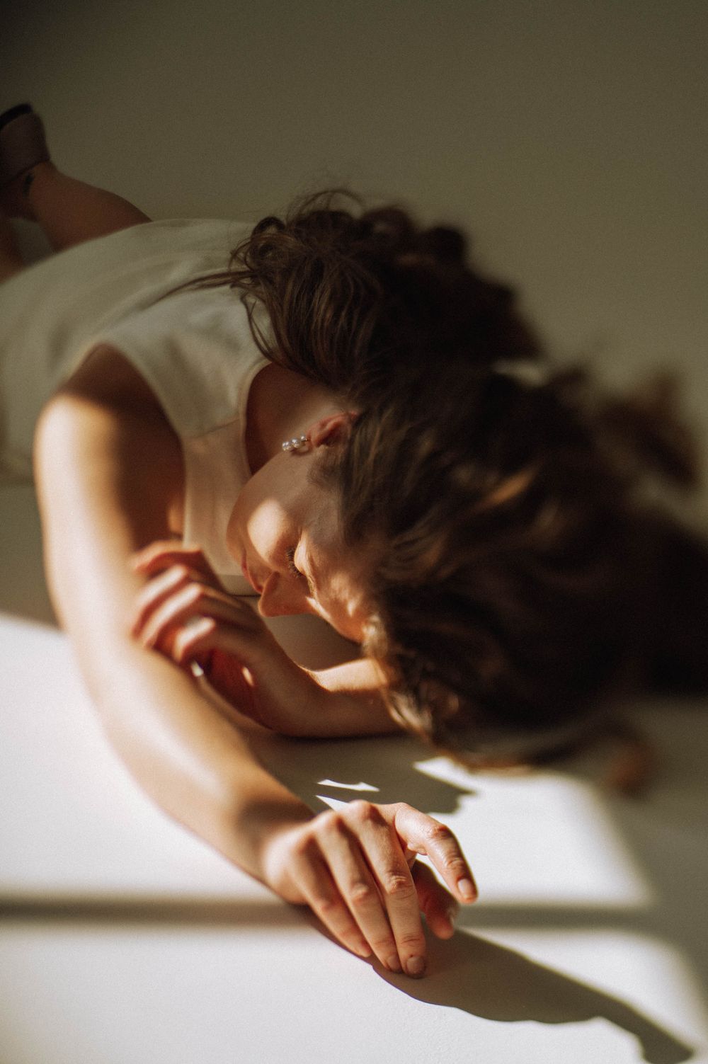 Artistic close-up photo showing hands resting on white surface in dramatic lighting.