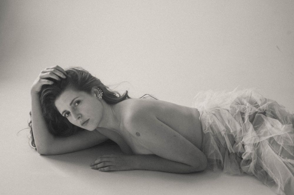 Minimalist boudoir photography with soft lighting and delicate white fabric.