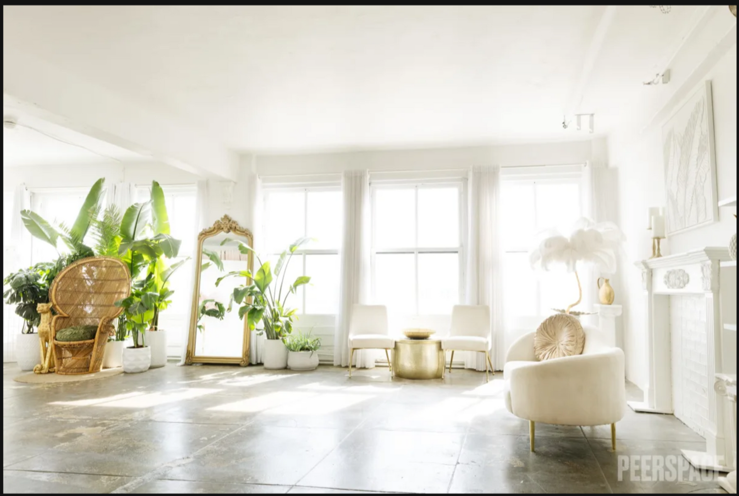 Bright sunlit room with houseplants, wicker furniture, and a white armchair in a minimalist bohemian style space.