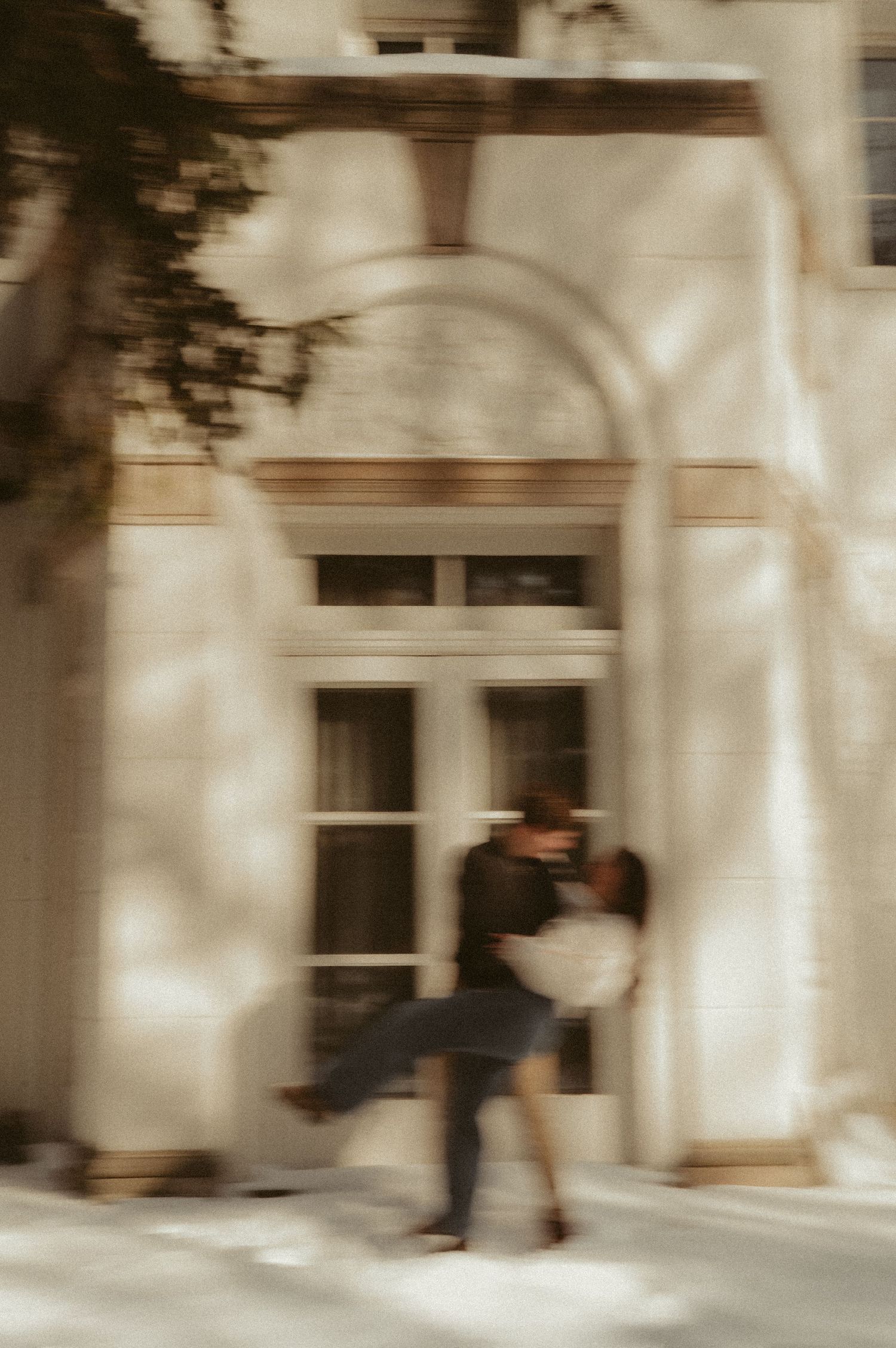 A series of blurred motion shots showing a figure in white moving gracefully through a bright architectural space.