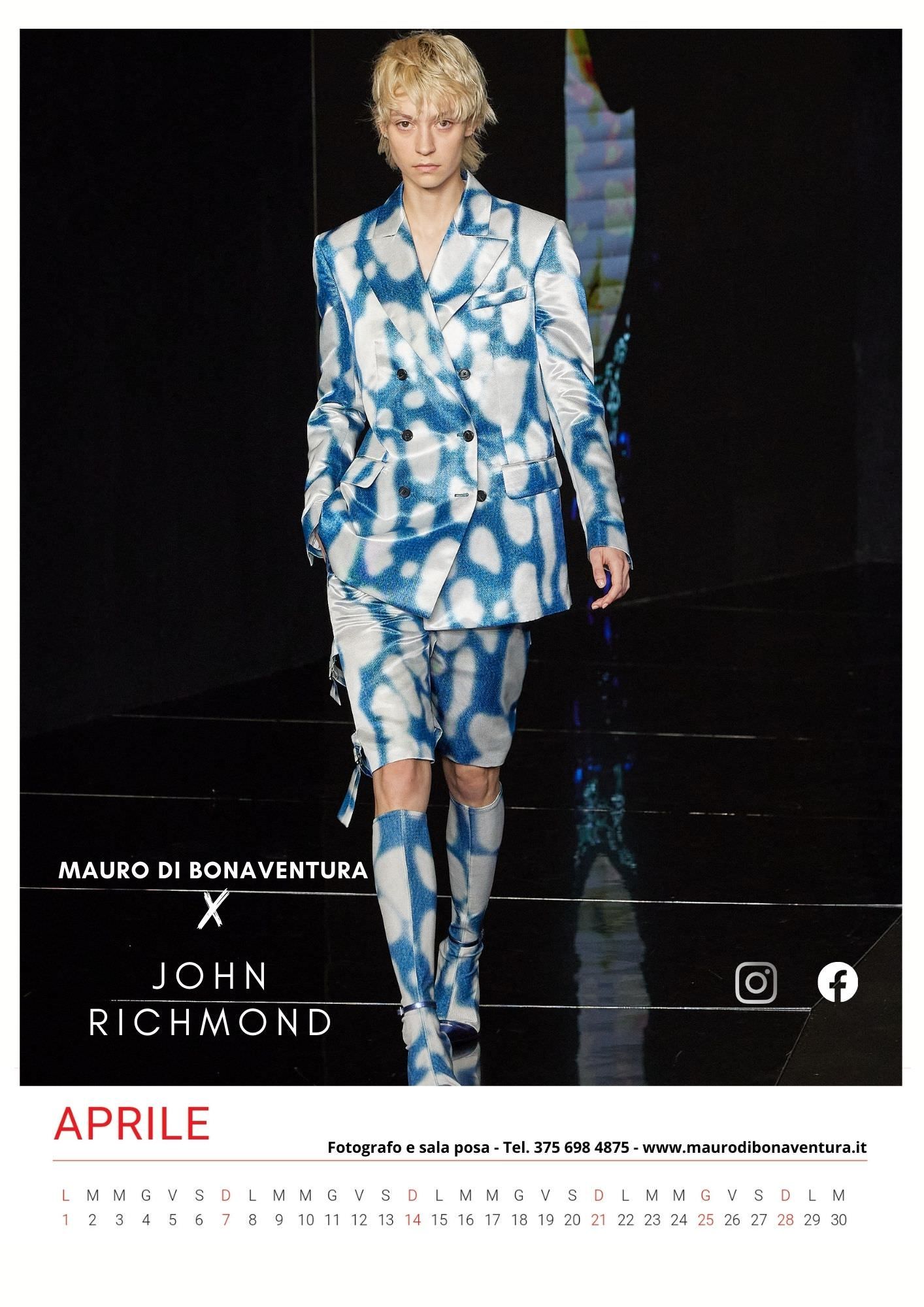 Blue and white tie-dye print suit with matching boots on dark runway.