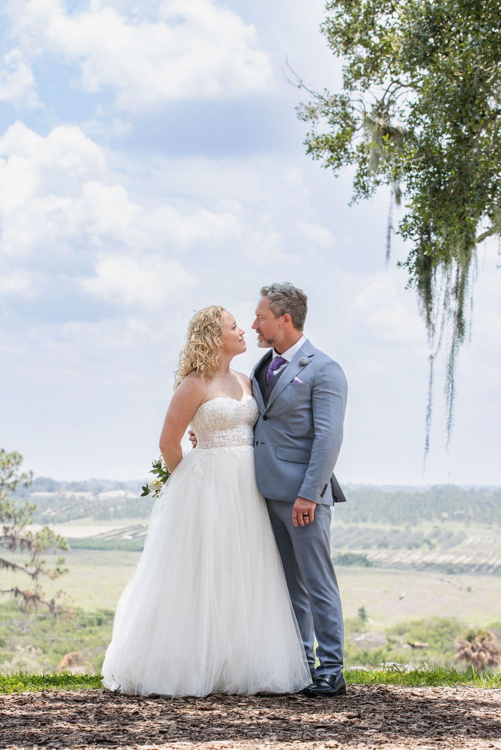 Bride and groom sharing a quiet moment beneath a tree with sweeping views at Bok Tower Gardens, Lake Wales, FL.