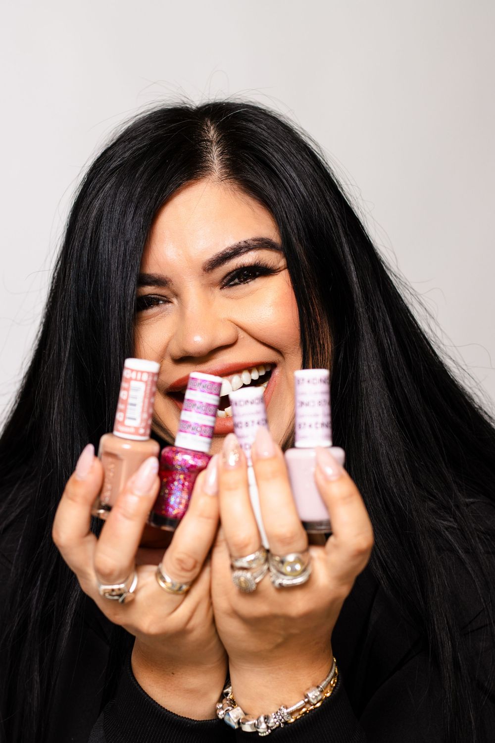 Lake Nona nail tech grinning ear to ear, proudly holding colorful nail powders during her studio branding session.
