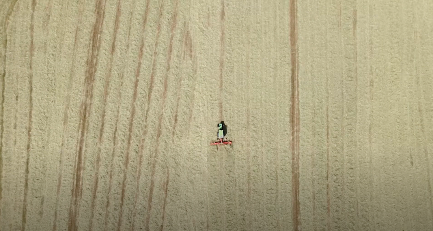 A tiny figure appears suspended in the middle of a vast beige textured wall or surface.