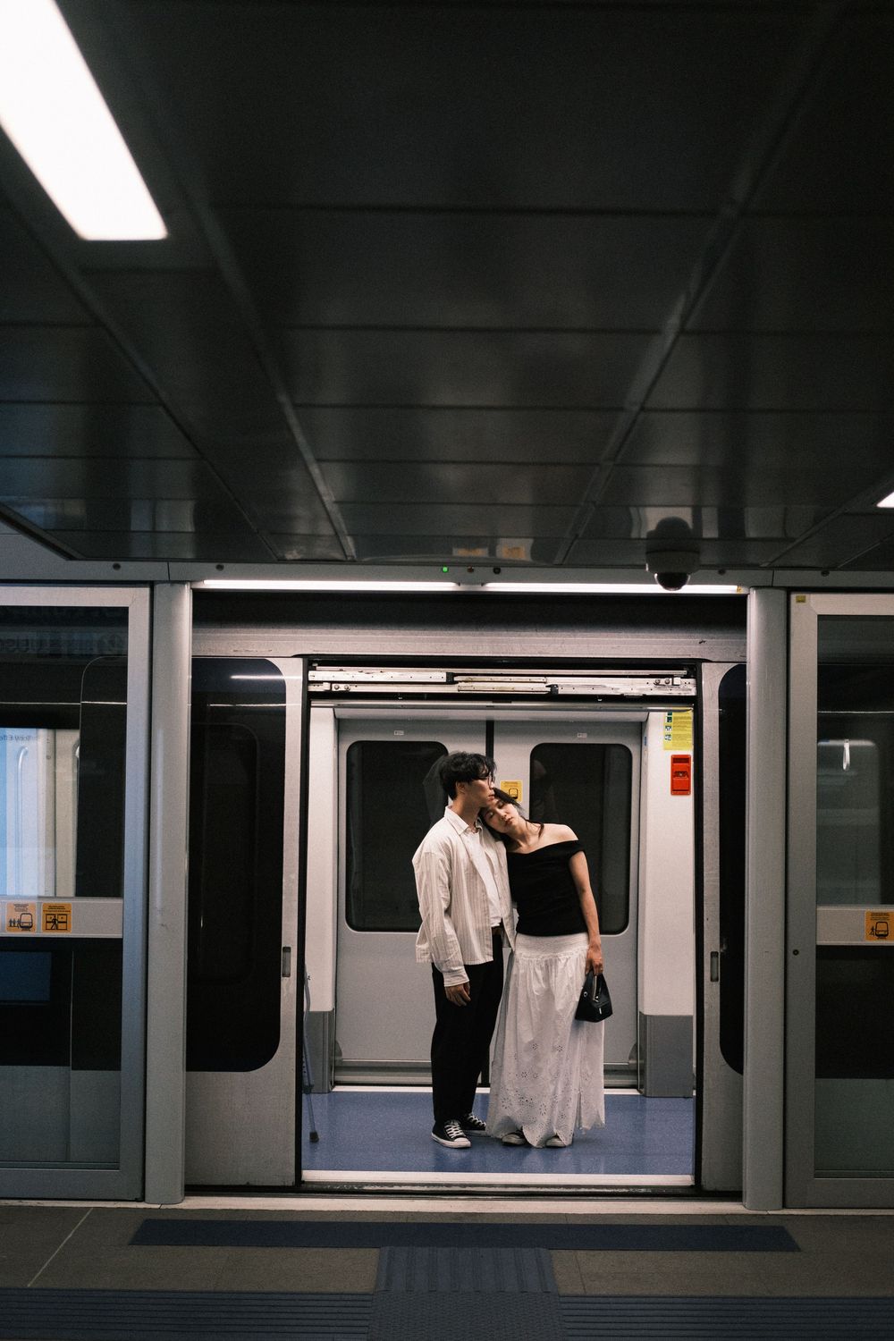 Couple standing in Milan metro, cinematic Milan couple photoshoot with candid Hong Kong–style lighting.