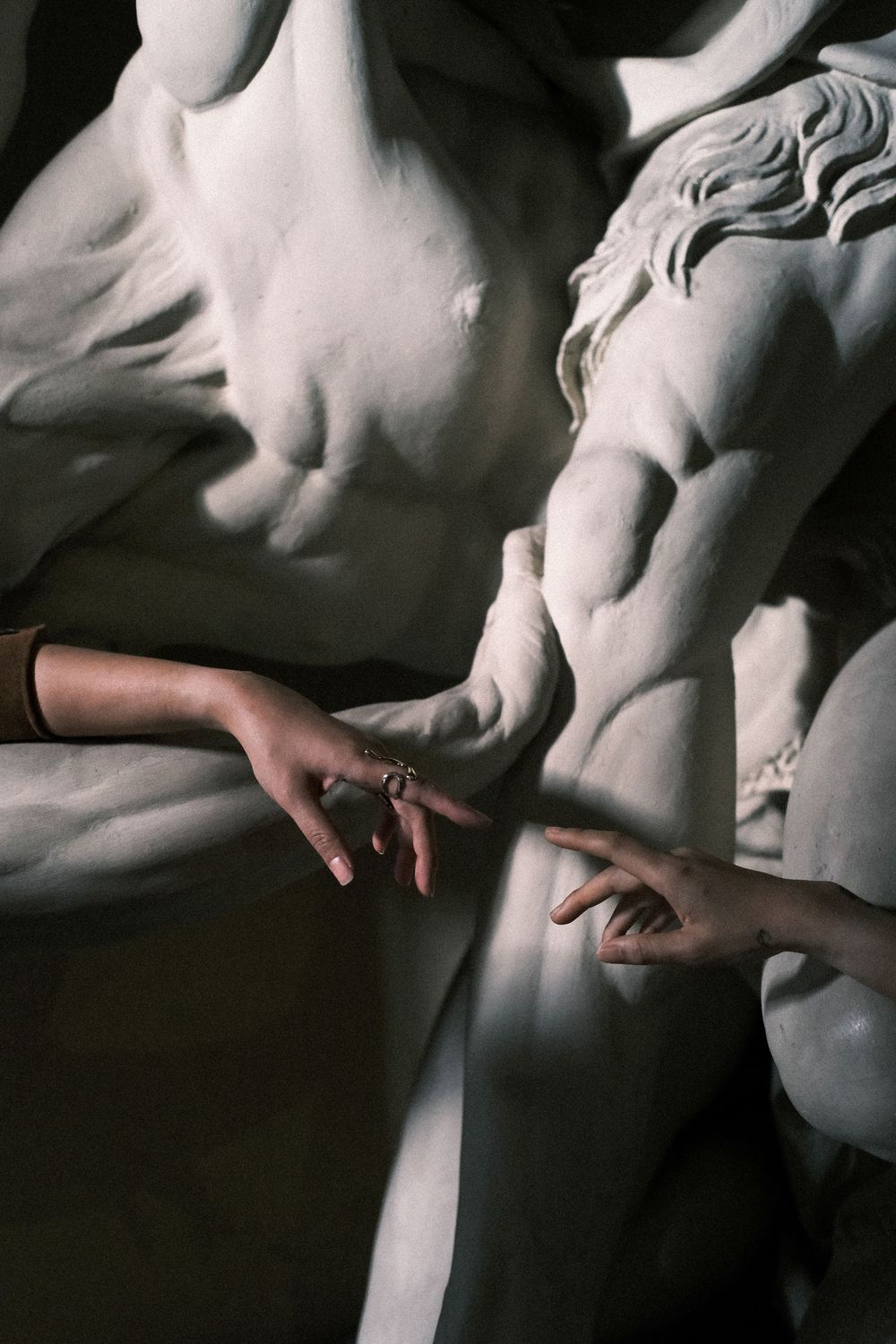 Artistic engagement detail of hands on marble sculpture, cinematic candid editorial moments.
