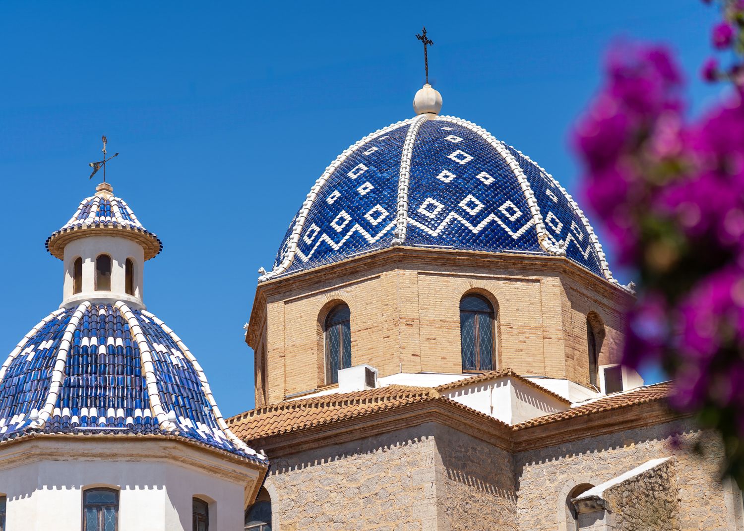 Blue and white domed church towers with ornate patterns against a bright sky.