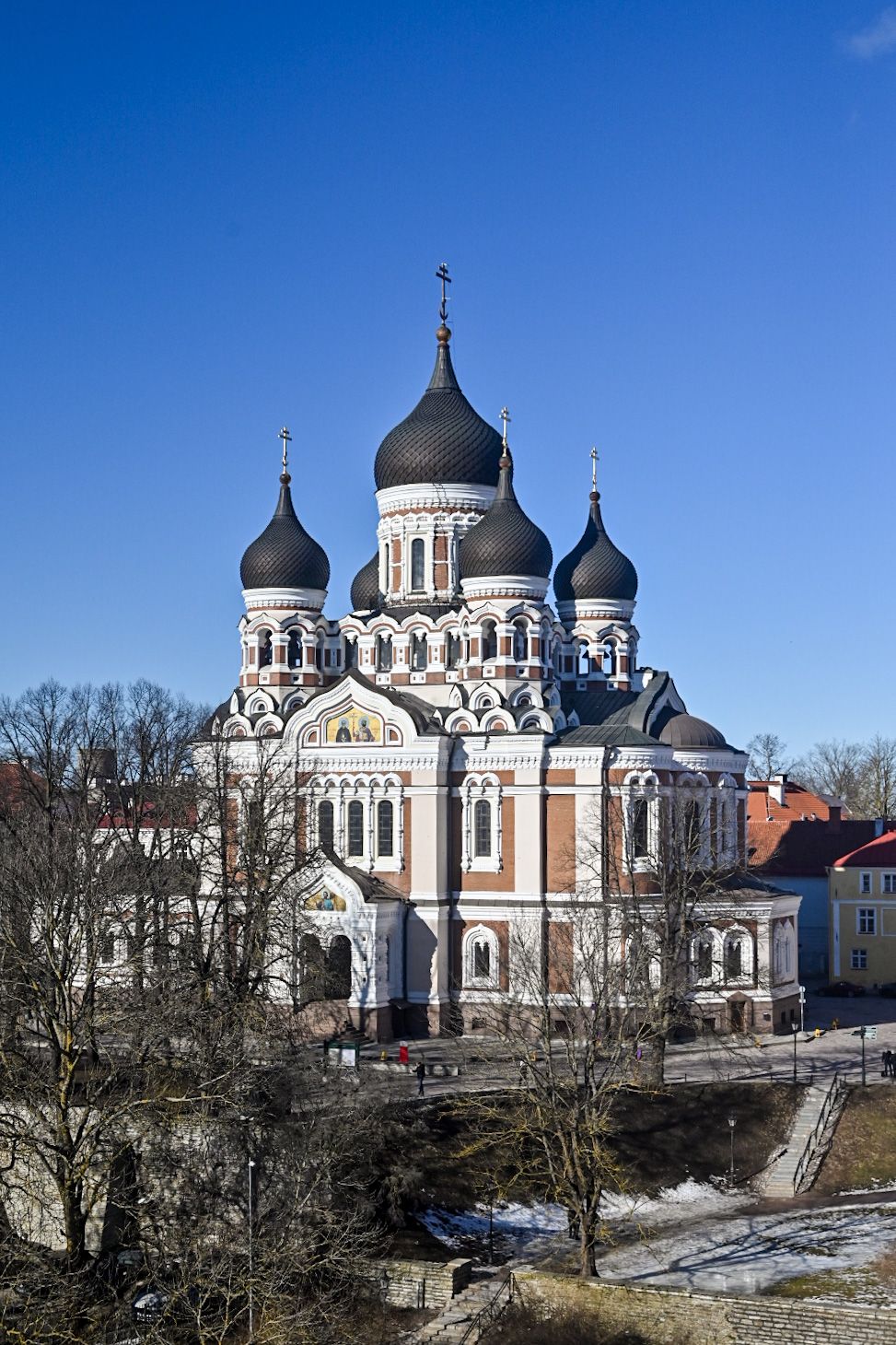 Alexander Nevsky Cathedral with black onion domes stands majestically against bright blue sky.