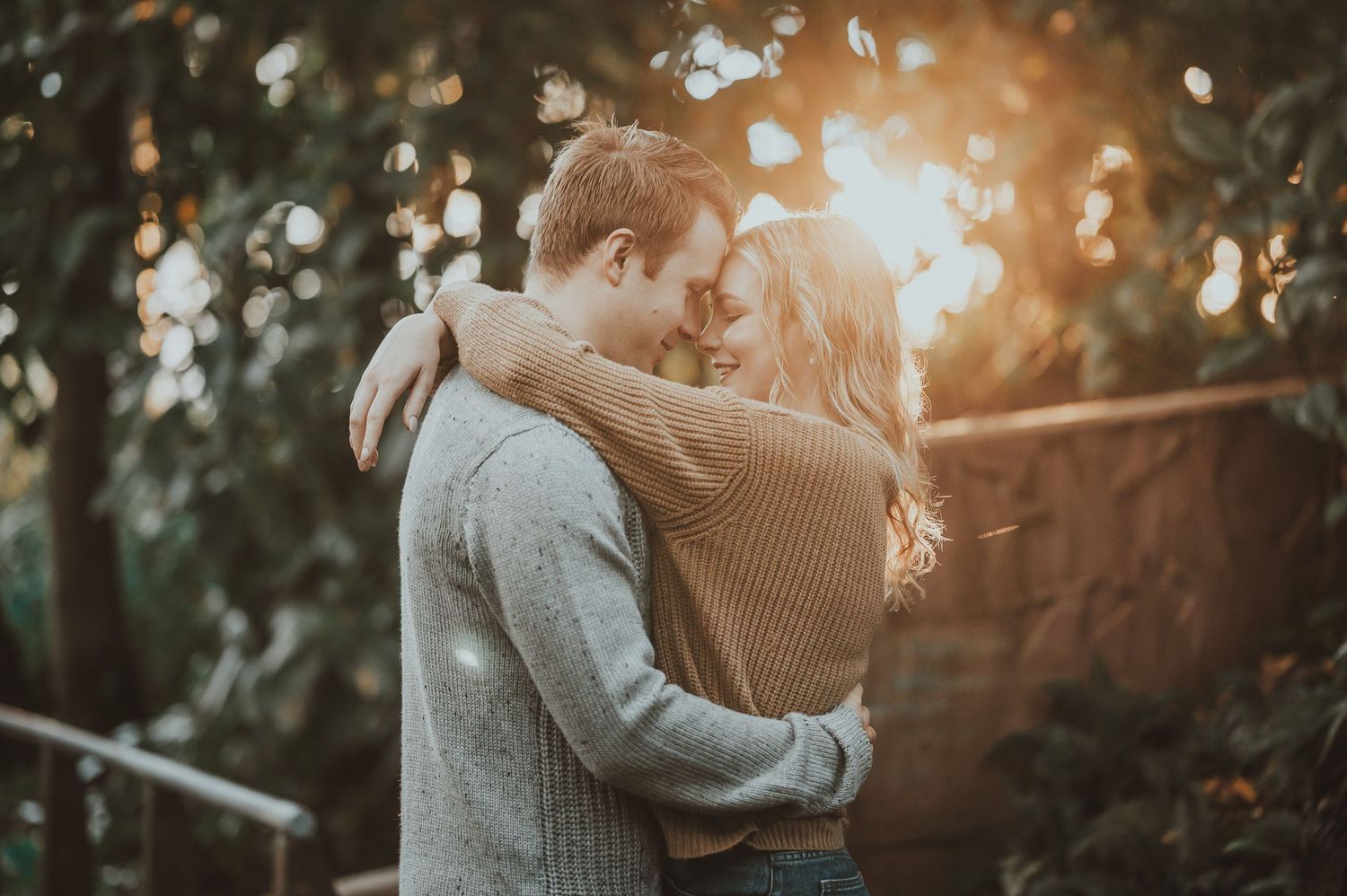 Romantic couple embracing in sunlit forest setting.
