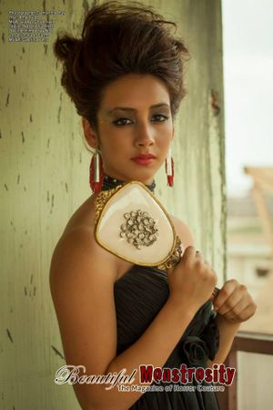 Vintage inspired portrait with updo hairstyle and ornate handbag against textured wall.
