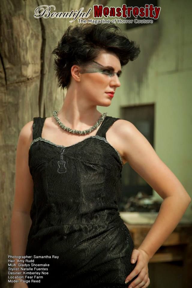 Fashion model wearing vintage-style black dress and statement necklace in moody dramatic portrait.