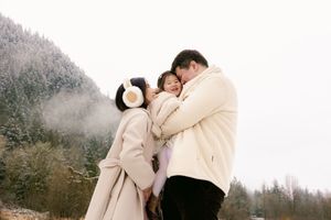 Family  a snuggly hug against a snowy mountain backdrop.