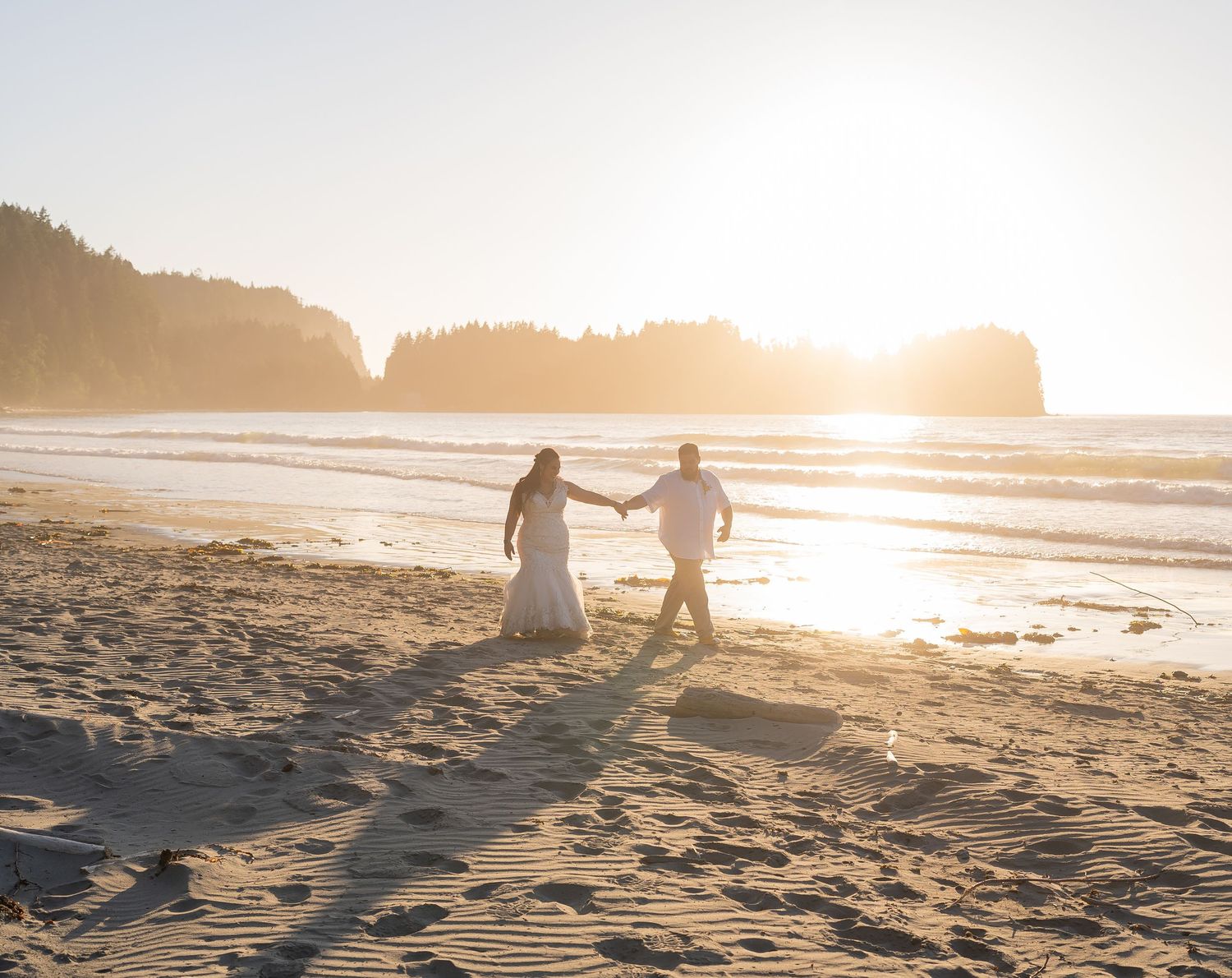 Couple walking hand in hand on beach at golden sunset.