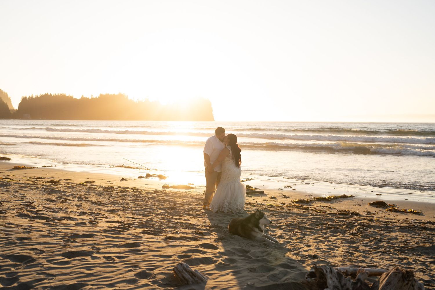 Silhouetted couple embracing on beach during dramatic sunset.