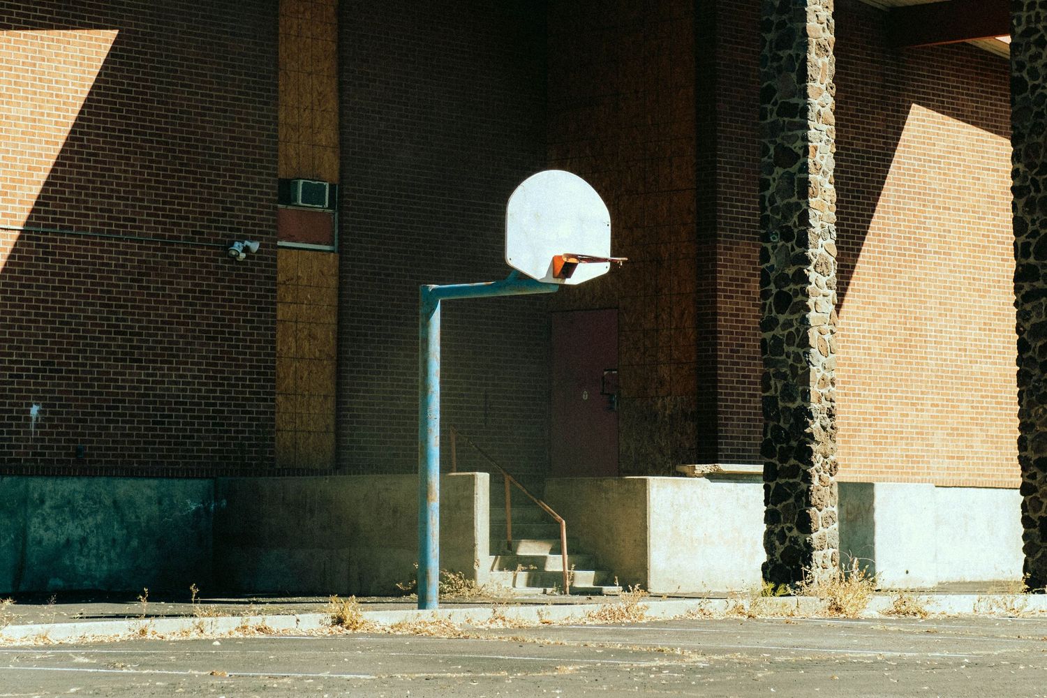 Solitary basketball hoop and backboard mounted on brick wall in empty urban setting.