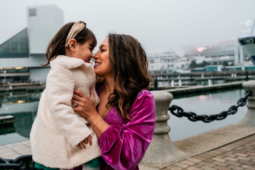 An intimate moment shared on a waterfront boardwalk with boats visible in the background.