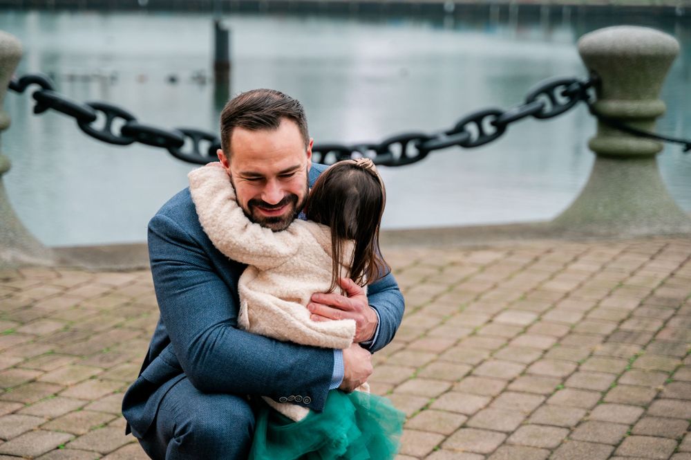 A joyful embrace captured on a brick pathway near a waterfront.