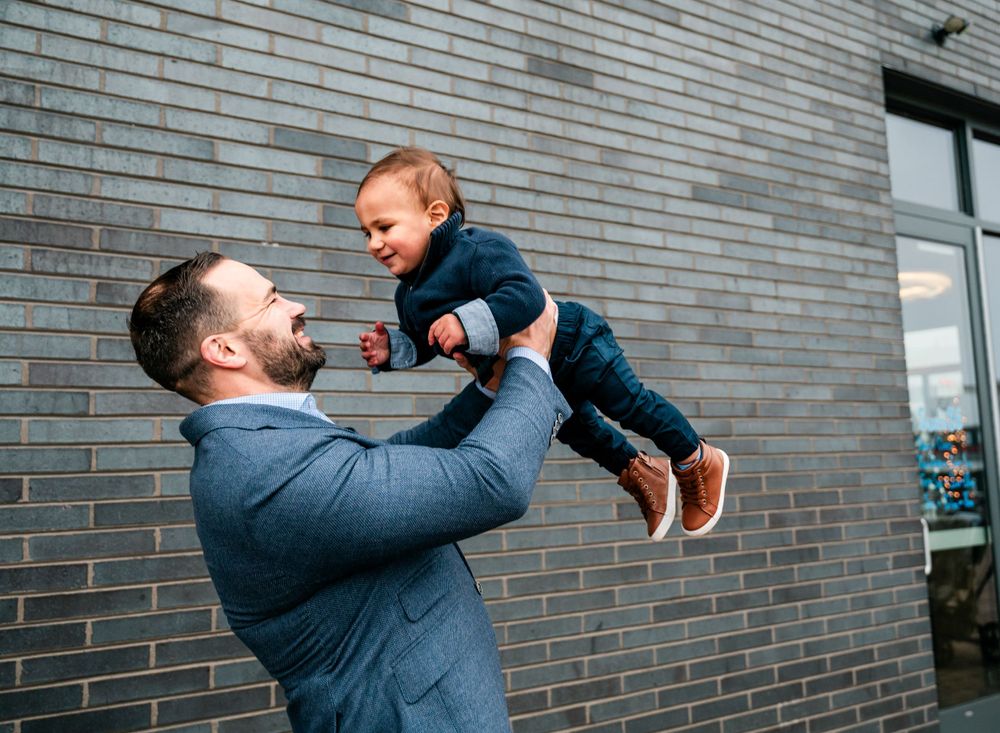 A playful moment between two people against a grey brick wall background.