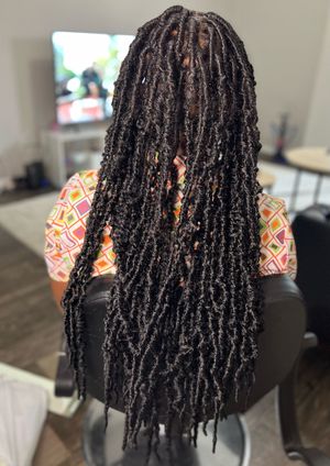 Long dreadlocks hairstyle shown from the back view displaying neat dark locs cascading down past shoulder length.