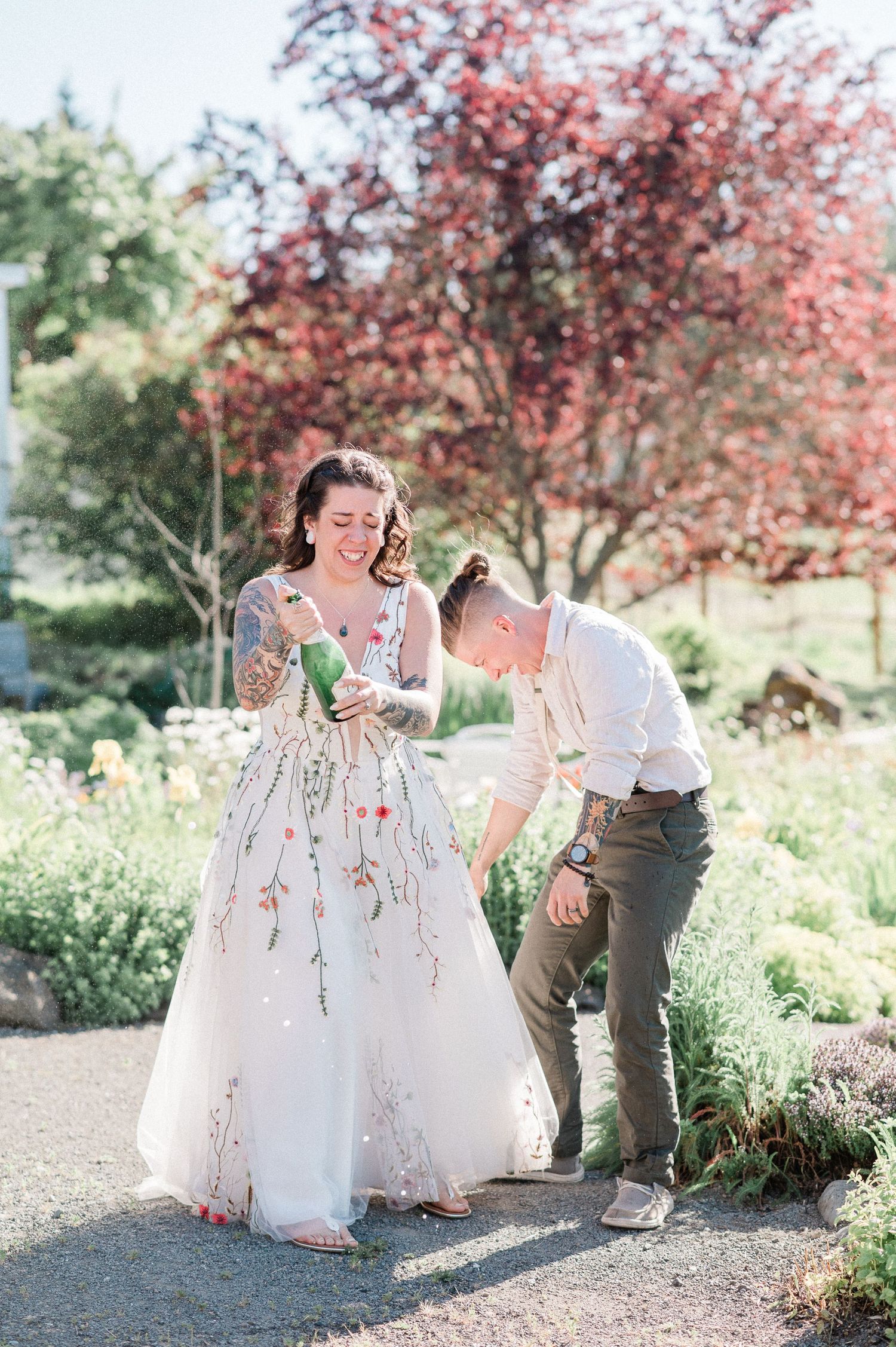 Couple shares playful moments under pink flowering trees in a romantic garden photoshoot.